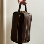 Necessaire de couro legítimo Dani By Tascheers com fechamento em zíper metálico superior, formato estruturado e acabamento artesanal premium.