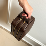 Necessaire de couro legítimo Dani By Tascheers com fechamento em zíper metálico superior, formato estruturado e acabamento artesanal premium.