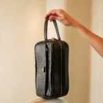 Necessaire de couro legítimo Helena By Tascheers com fechamento em zíper metálico superior, silhueta estruturada e acabamento artesanal premium.