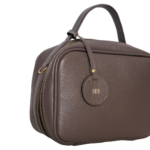 Necessaire de couro legítimo New Bárbara Pequena By Tascheers com formato compacto, fechamento em zíper metálico e acabamento artesanal estruturado.
